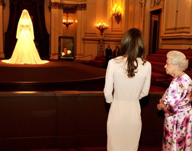 Kate Middleton e Rainha Elizabeth II olham de longe o vestido de noiva que a Duquesa de Cambridge usou no casamento com o Príncipe William