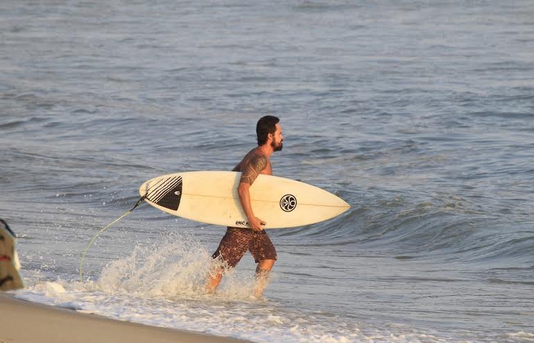 Paulinho Vilhena surfa na praia da macumba