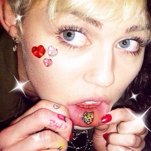 Gato triste, em 2014, parte interior do lábio: Miley fez essa tatuagem durante o tempo que passou no estúdio com Wayne Coyne. Ela mostra um gatinho amarelo com uma lágrima azul.