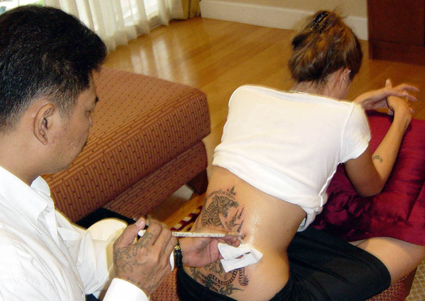 A tatuagem foi feita em estilo tailandês tradicional --- usando grandes agulhas manualmente e foi feita pelo famoso tatuador tailandês artista Noo Sompong Kanhphaiin, que também fez um tigre de Bengala. Jolie teve que se ajoelhar em oração durante o processo de tatuagem como o ritual determina.
