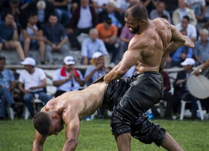 Em festival, atletas lutam com corpo coberto de azeite de oliva para homenagear apóstolos