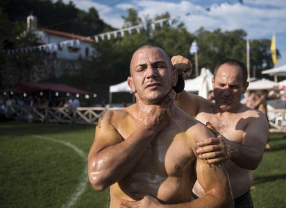 Em festival, atletas lutam com corpo coberto de azeite de oliva para homenagear apóstolos