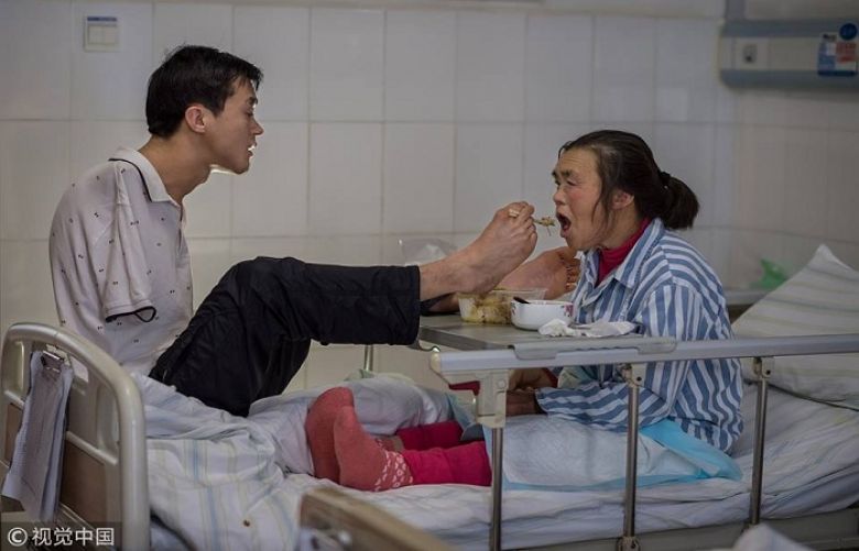 Homem sem braços alimenta mãe com pés